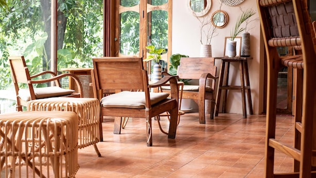 A room with large windows, wicker furniture, and a wooden floor. - Tints of Blue Hotel (Bangkok)