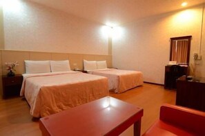 A hotel room with two beds, a desk, and a chair.