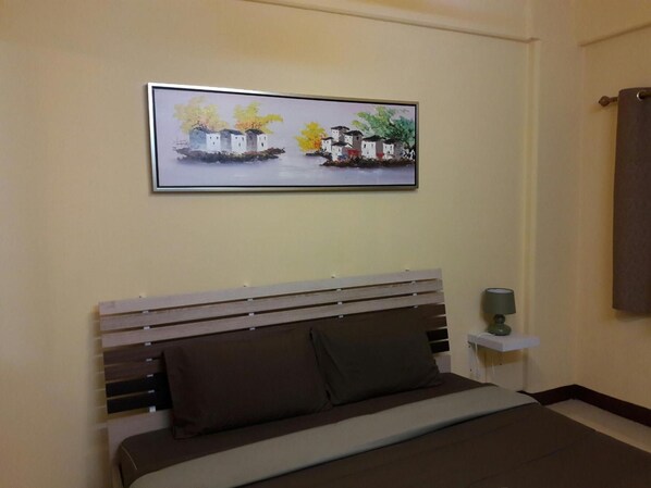 Une chambre à coucher avec un lit, une table de chevet, une lampe et un tableau encadré au mur.