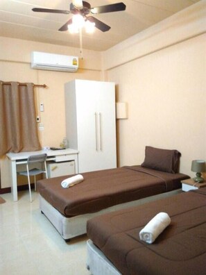 A hotel room with two beds, a desk, a chair, a ceiling fan, and an air conditioning unit. - Navavilla (Khlong Luang)