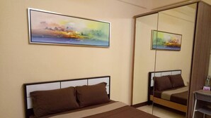 Una habitación de hotel con una cama, un espejo grande y dos cuadros en la pared.