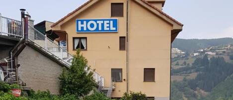 Un hotel con letrero, asientos al aire libre y vistas del paisaje circundante.