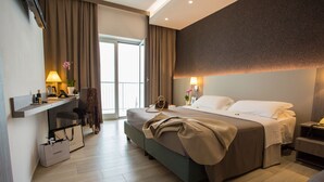 A hotel room with a bed, a desk with a lamp, a chair, and a view of the outdoors. - Hermitage Hotel (Silvi)