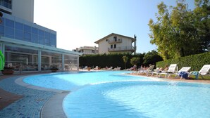 A swimming pool with lounge chairs and a glass-enclosed building. - Hermitage Hotel (Silvi)