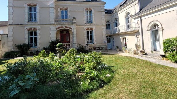 Un grand bâtiment à deux étages, doté d’une façade symétrique, de nombreuses fenêtres et d’une entrée centrale avec une porte rouge.