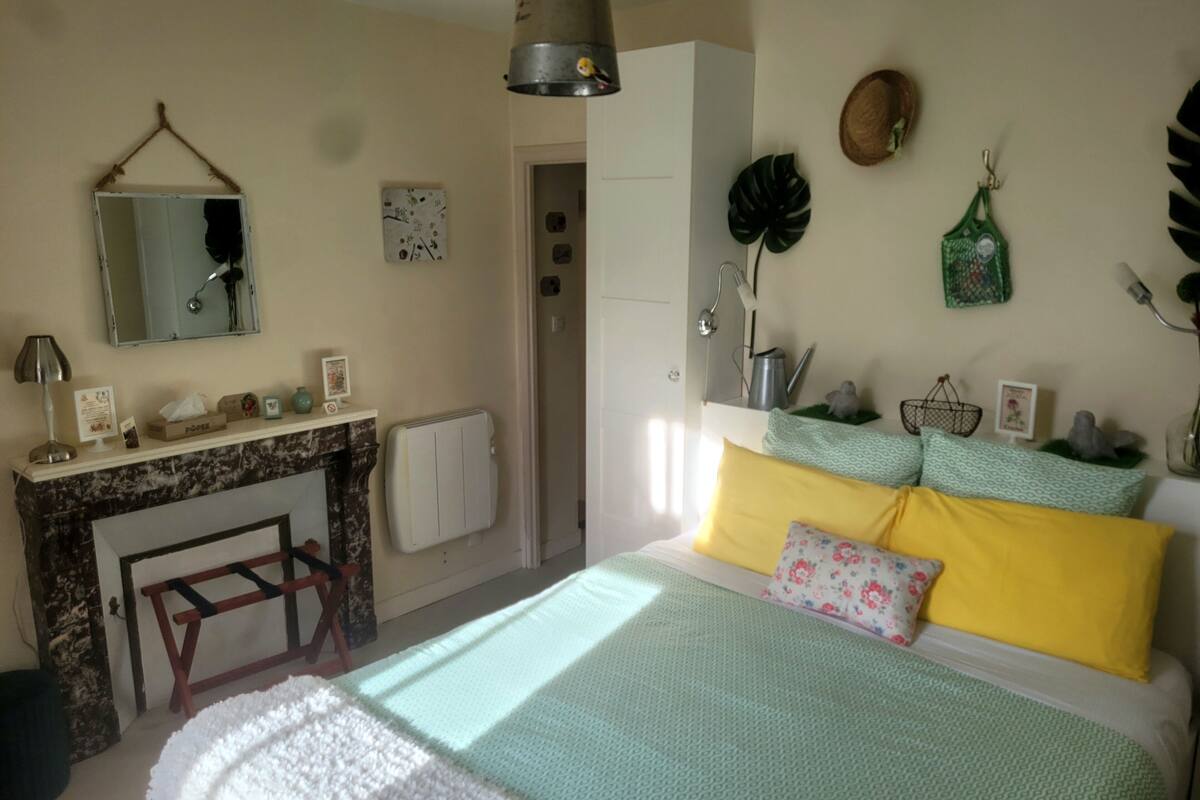 Een slaapkamer met een bed, een dressoir, een spiegel, een radiator en een raam.