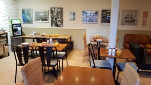 Un espace repas avec des tables et des chaises, des produits pour le petit-déjeuner et un réfrigérateur.
