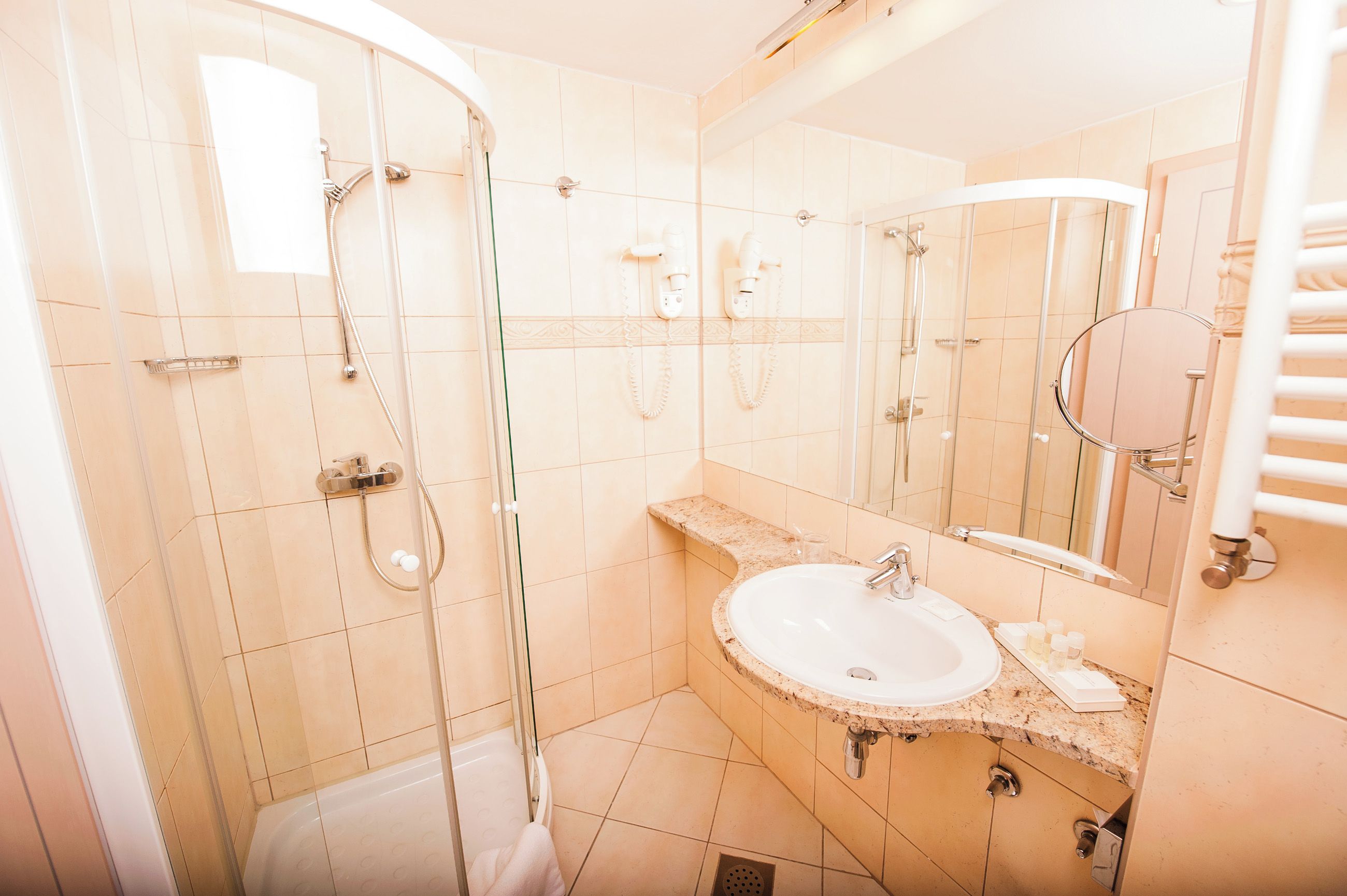 A bathroom with a glass-enclosed shower, a sink, and a mirror.