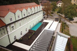 Un edificio con piscina, zona exterior techada y vista a la calle.