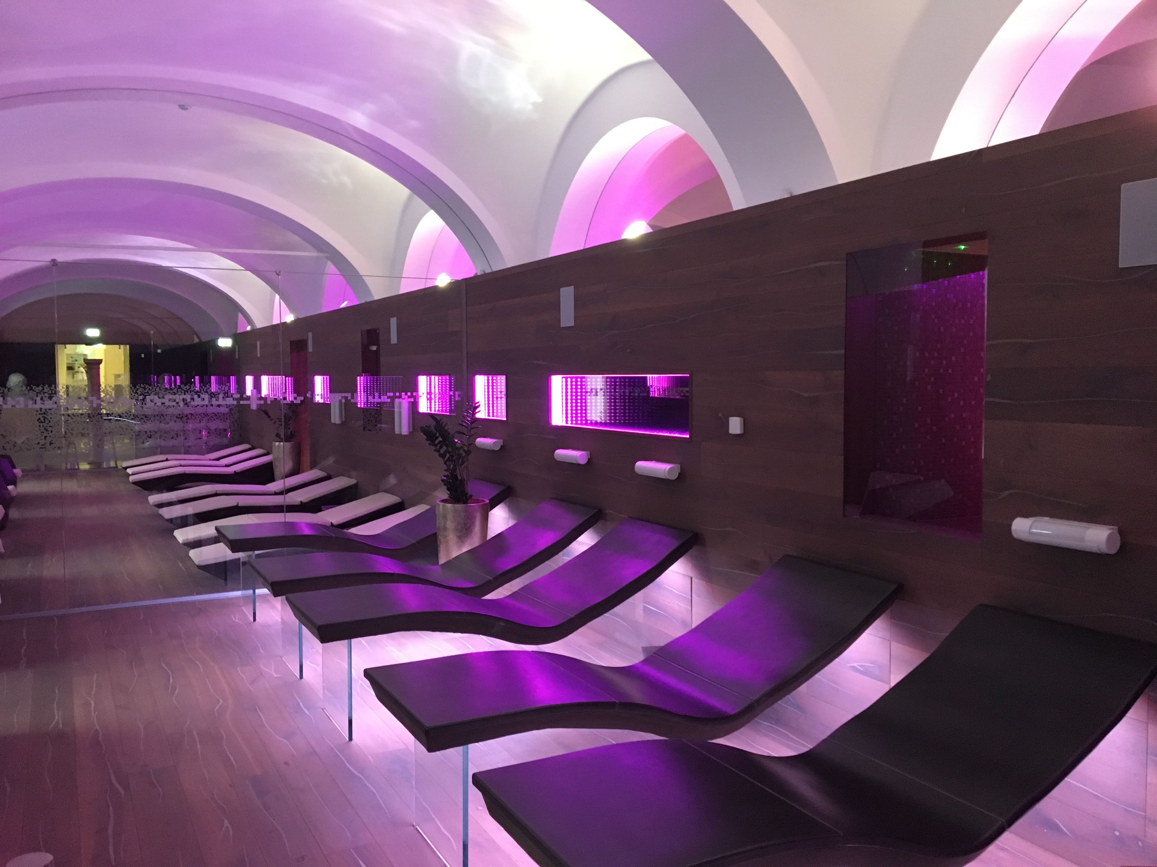 A modern spa with multiple treatment rooms, each with a massage table and a wall-mounted LED light panel.