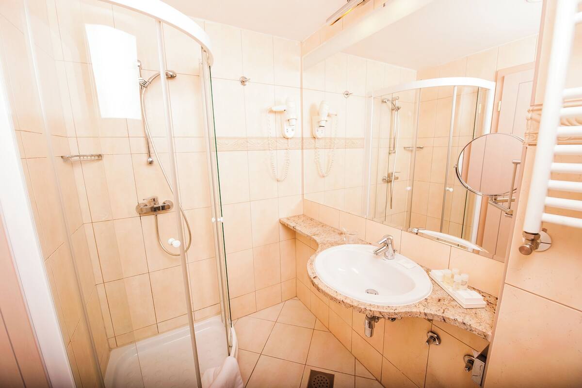 A bathroom with a glass-enclosed shower, a sink, and a mirror.