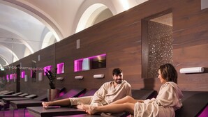 Um spa moderno com paredes de madeira, um amplo claraboia e uma fileira de macas de massagem.