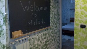 A blackboard with "Welcome to Milady" written on it, a radiator, and a bed in the background. - B&B La Grotta (Castel Giorgio)