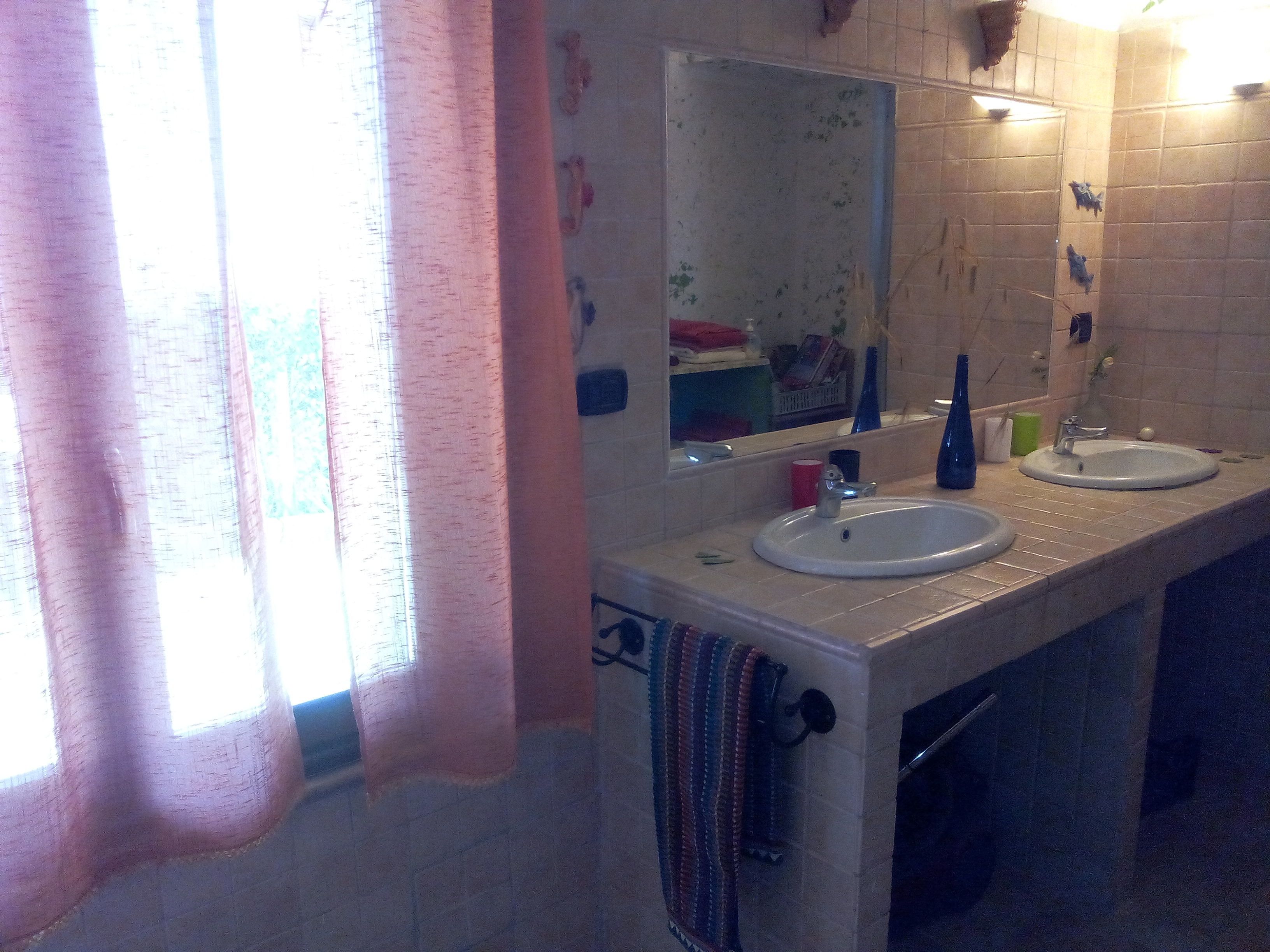 Un baño con dos lavamanos, un espejo y un perchero para toallas.