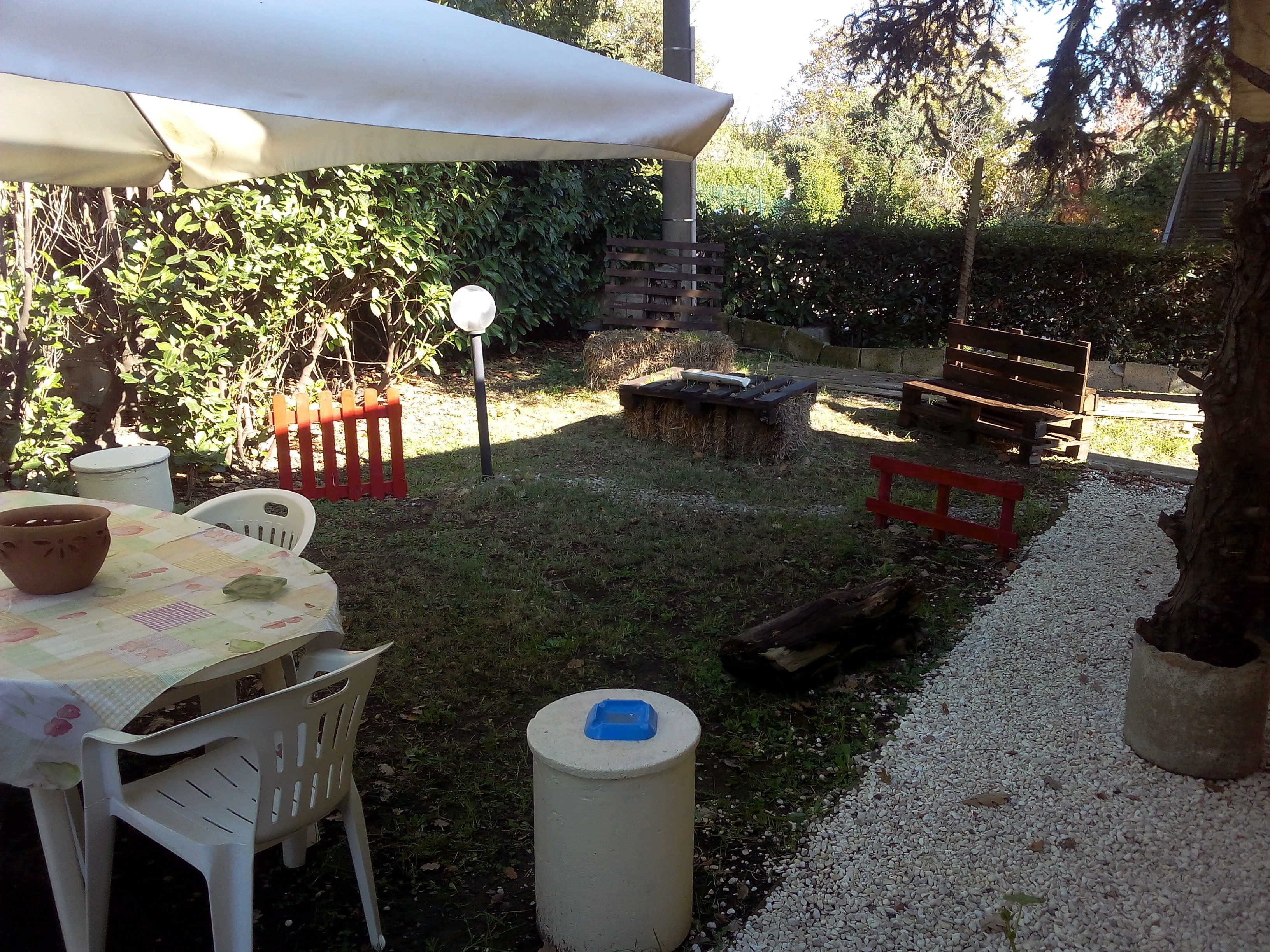 A patio area with a table set for dining, a covered seating area, and a gravel path.