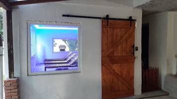 A room with a large window, a wooden door, and a brick wall.