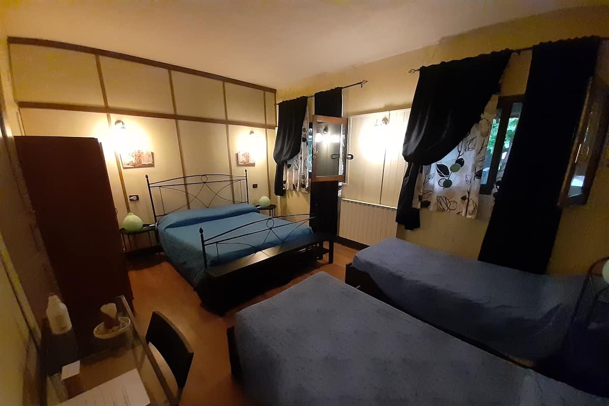 A bedroom with two beds, a nightstand, a dresser, and a window with curtains.