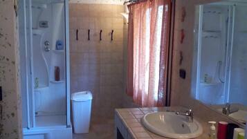 Un baño con ducha, inodoro, lavabo y espejo.