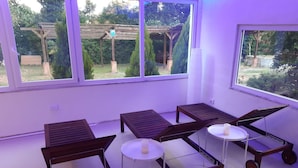 A room with four wooden tables with wheels, a white table, and a window overlooking a garden. - B&B La Grotta (Castel Giorgio)