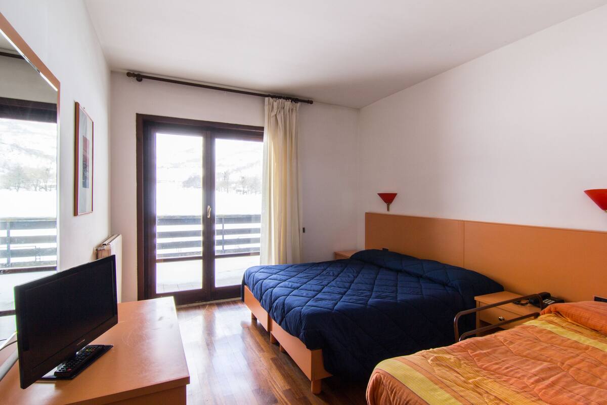 Een hotelkamer met een bed, een bureau met een televisie en een raam met uitzicht op het omliggende landschap.