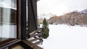 A snowy landscape with a mountain in the background, a wooden staircase, and a small tree in the foreground. - Hotel Du Park (Opi)