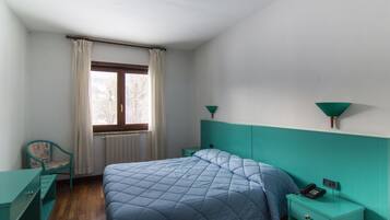 Una camera da letto con un letto, una sedia, un comodino e una finestra con tende.