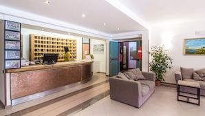 A reception area with a counter, seating, a plant, and a wall with framed pictures. - Hotel Du Park (Opi)