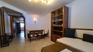 A room with a wooden dining table, chairs, a sofa, and a built-in bookshelf. - Aparthotel Buchauer Tirol (Thiersee)