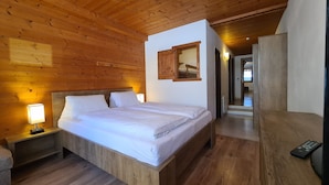 A wooden-paneled bedroom with a bed, bedside lamp, and a mirror. - Aparthotel Buchauer Tirol (Thiersee)