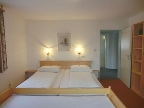 A double bed with two pillows, a wooden headboard, and two bedside lamps. - Buchauer-Tirol Landhaus Buchauer (Thiersee)