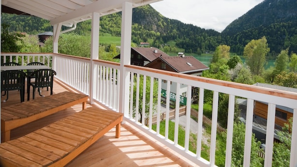 A wooden deck with a table and chairs, overlooking a valley with houses and mountains. - Buchauer-Tirol Landhaus Buchauer (Thiersee)