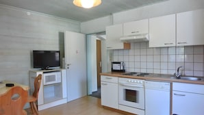 A compact kitchen with white cabinets, a microwave, a stove, and a sink. - Buchauer-Tirol Landhaus Buchauer (Thiersee)