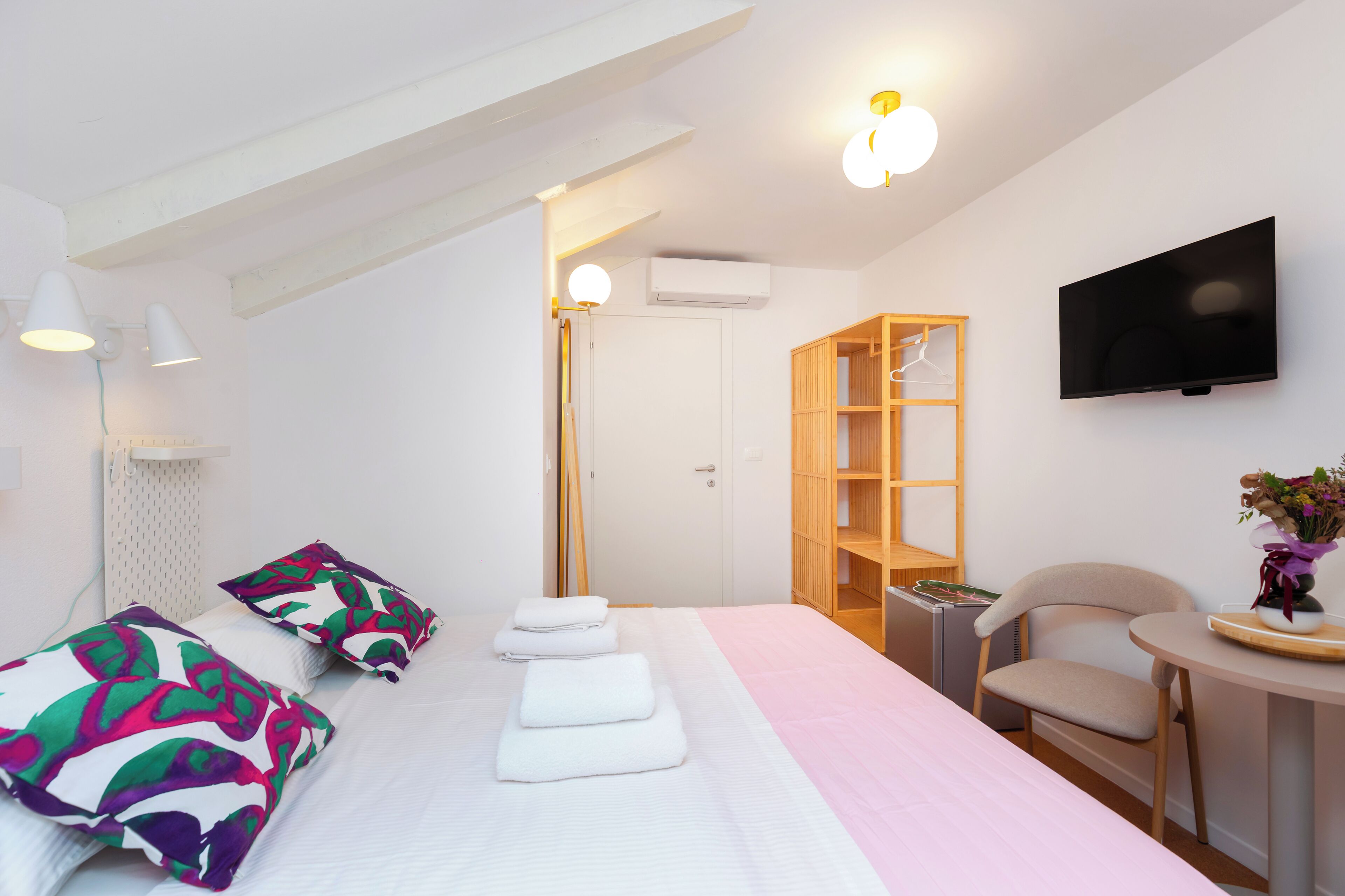 A hotel room with a bed, a chair, a TV, and a wardrobe.
