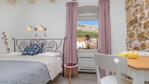 Una camera da letto con un letto, un tavolino con delle zucche, una sedia e vista su un paesaggio montuoso attraverso una finestra con tende.
