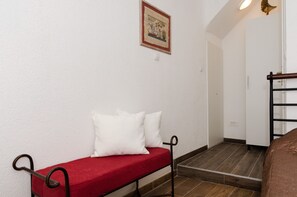A hallway with a red bench, a framed picture on the wall, and a door leading to another room.