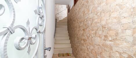 A staircase with stone walls and a metal railing.
