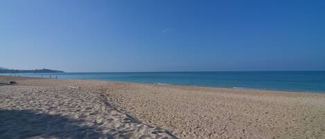 Una playa arenosa con cielo despejado y mar tranquilo.