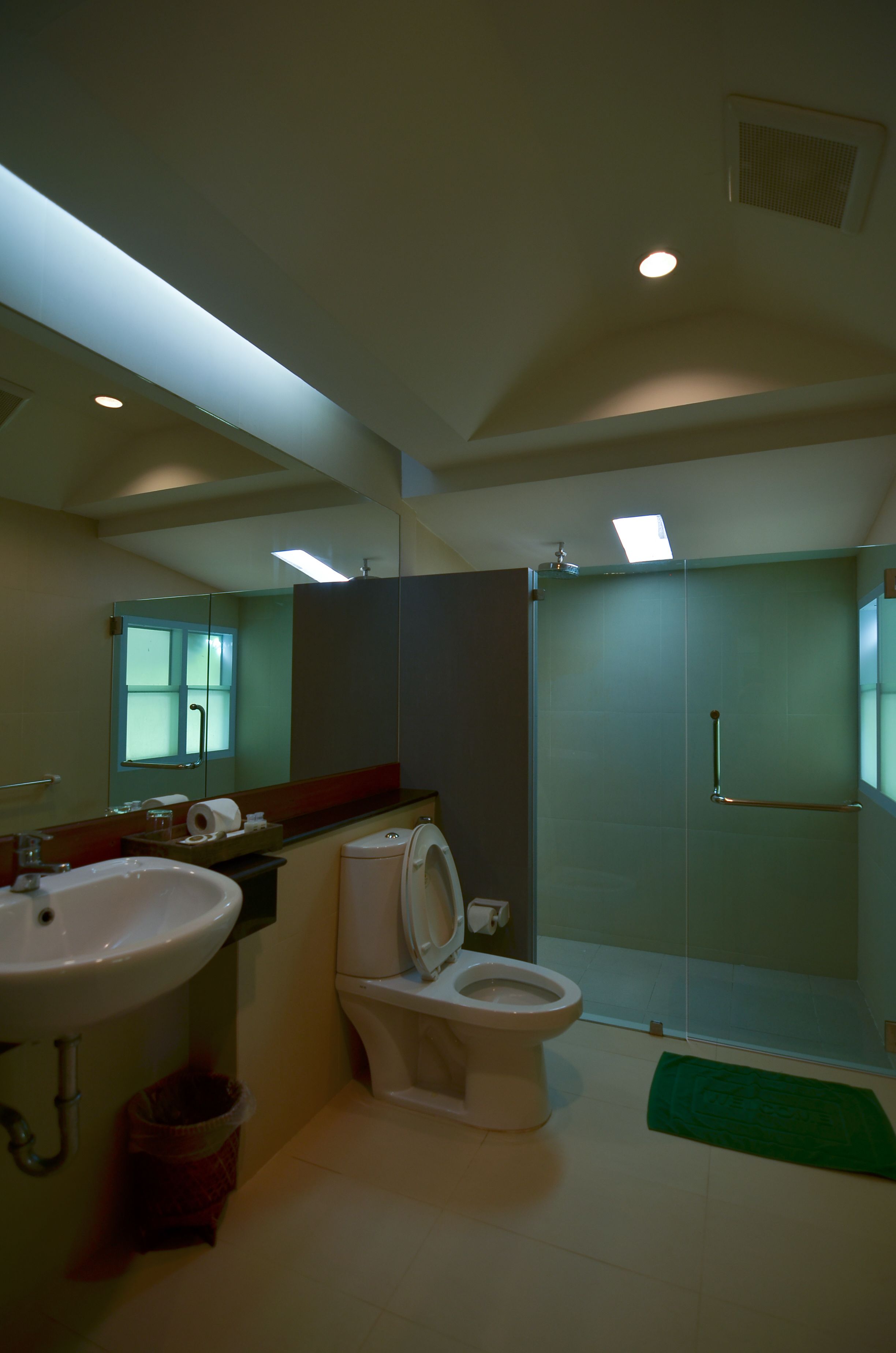 Un baño con lavamanos, inodoro y cabina de ducha de vidrio.