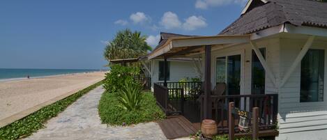 A beachfront property with a covered porch, a wooden deck, and a view of the beach.