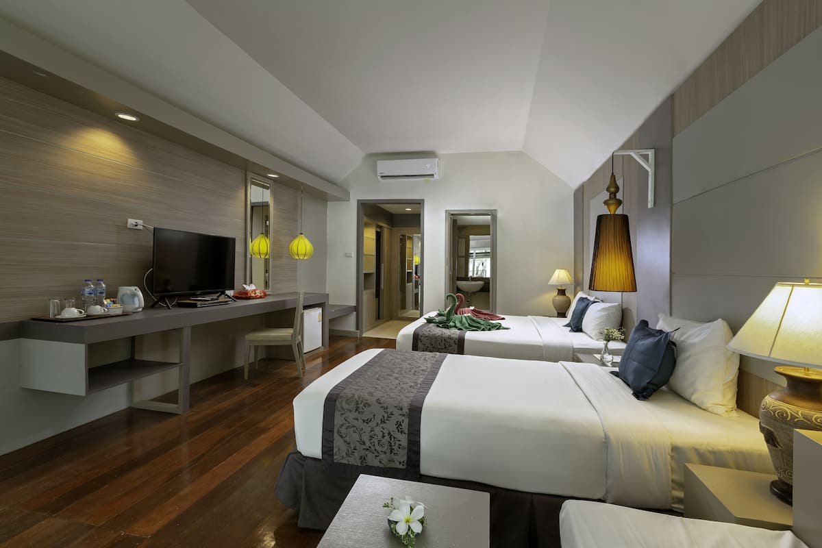 Une chambre d’hôtel avec deux lits, un bureau avec une télévision et un coin repas.