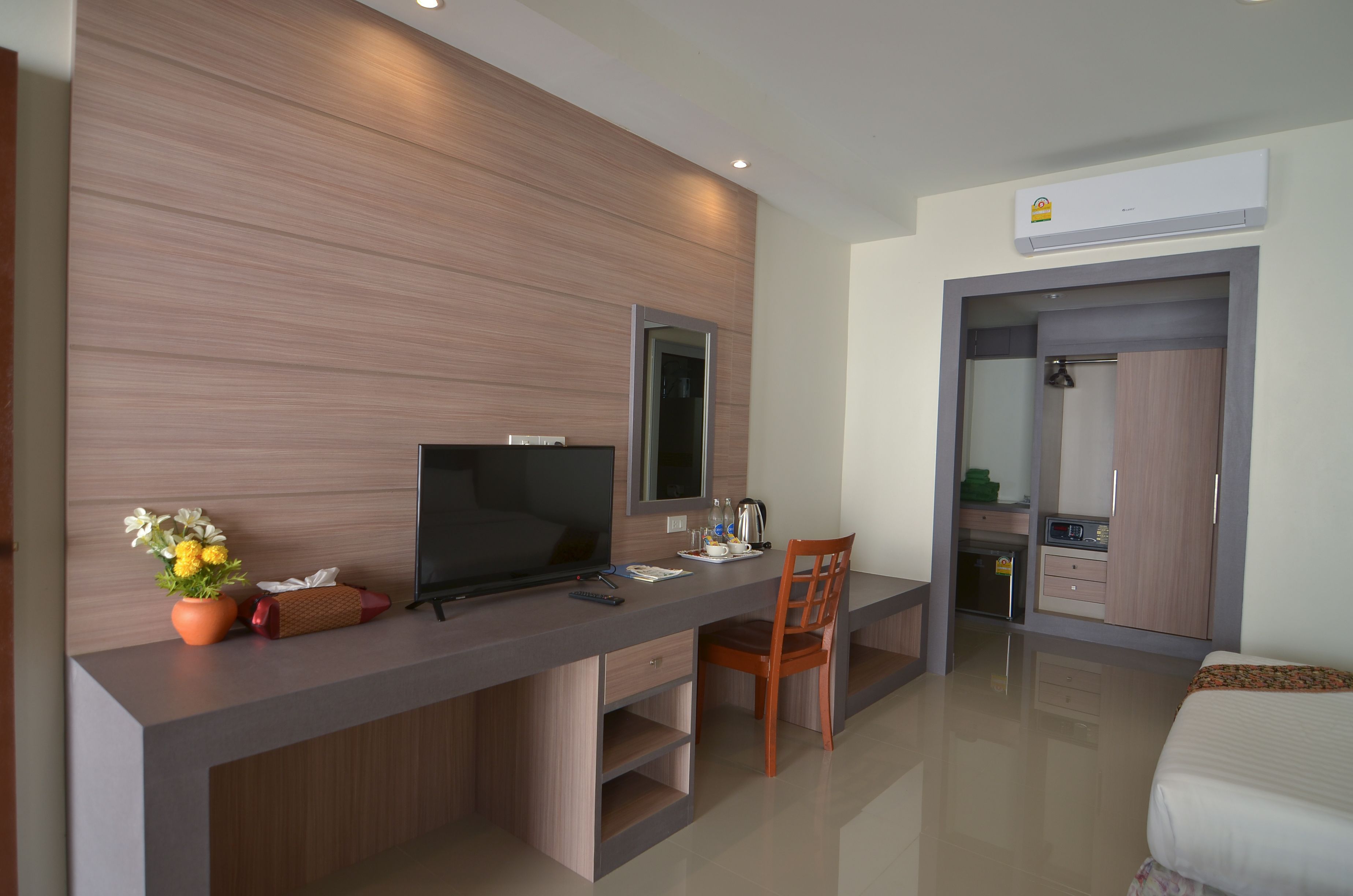 Une chambre d’hôtel moderne avec un mur d’accent en bois, un téléviseur à écran plat, un bureau avec une chaise, un lit et une armoire.