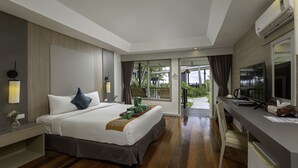 A modern hotel room with a large bed, a desk with a television, and a view of the outdoors.