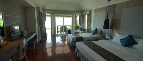 A hotel room with two beds, a desk with a television, and a balcony with a view.