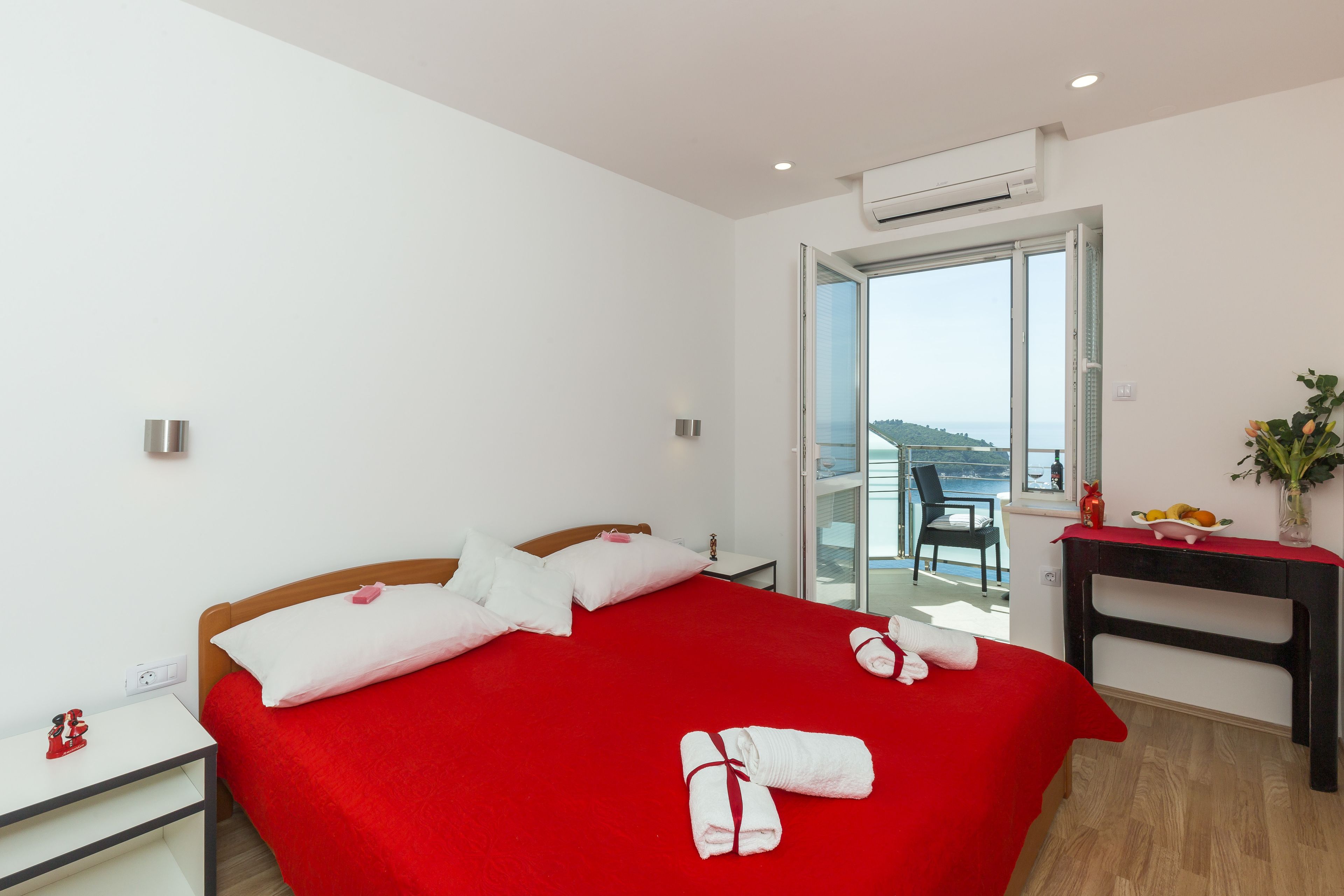 A hotel room with a large bed, a desk, and a view of the sea.