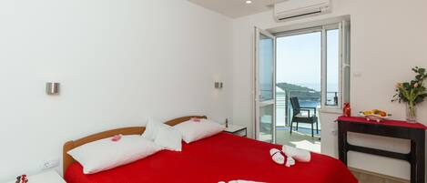 Quarto de hotel com uma cama grande, uma escrivaninha e vista para o mar.