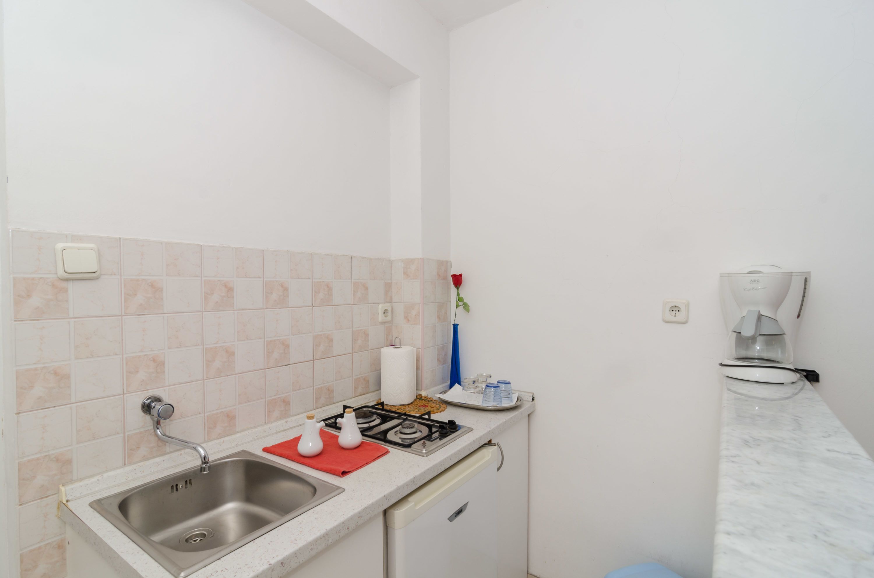 A small kitchen with a sink, stove, and a coffee maker.