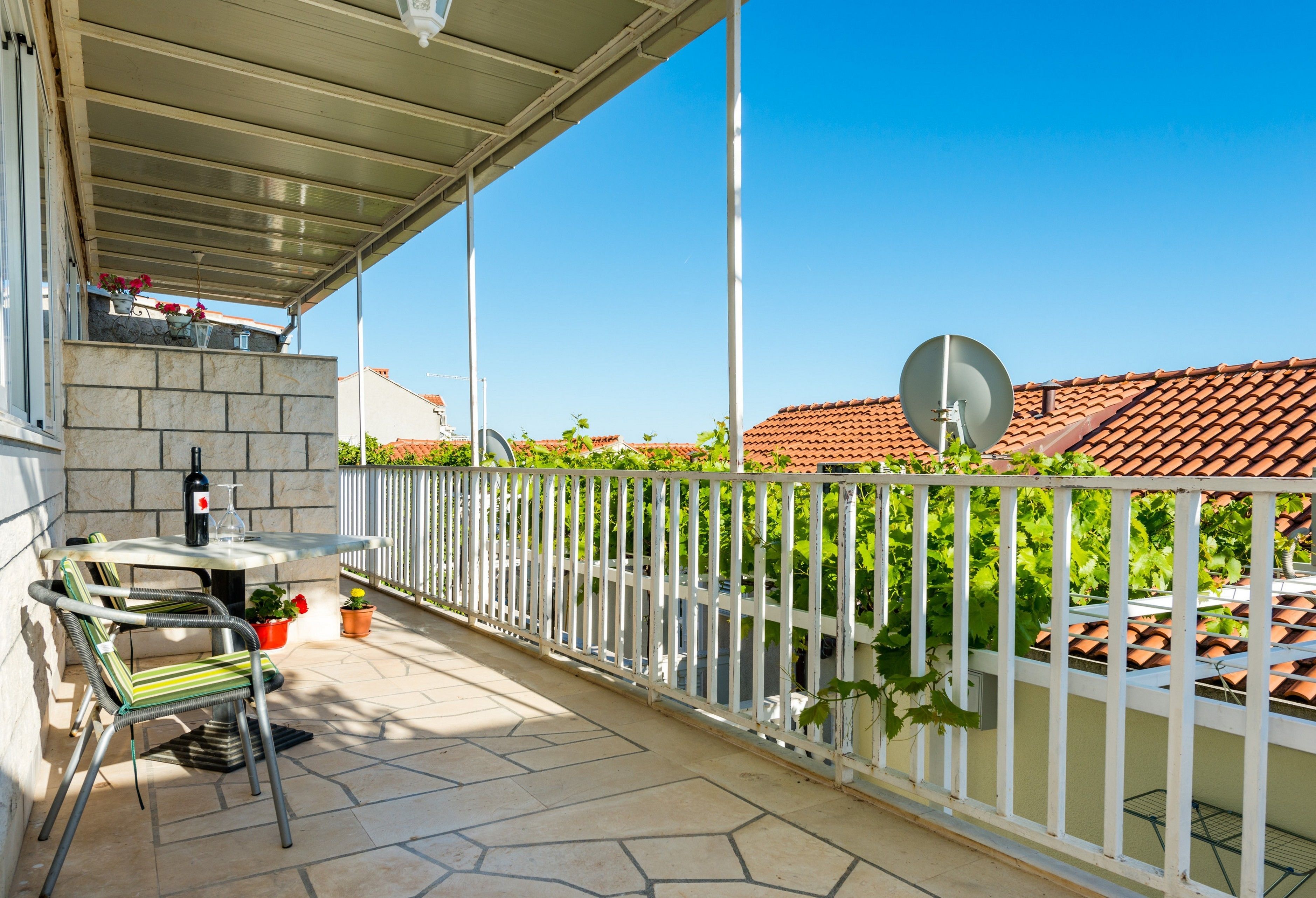 A covered outdoor area with a table and chairs, a potted plant, and a satellite dish.