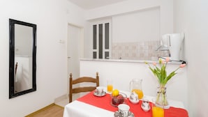 A small dining area with a table set for breakfast, a mirror, a coffee machine, and a vase with flowers. - Guesthouse Home Sweet Home (Dubrovnik)