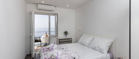 Un dormitorio con cama, mesita de noche, ventana y equipo de aire acondicionado.