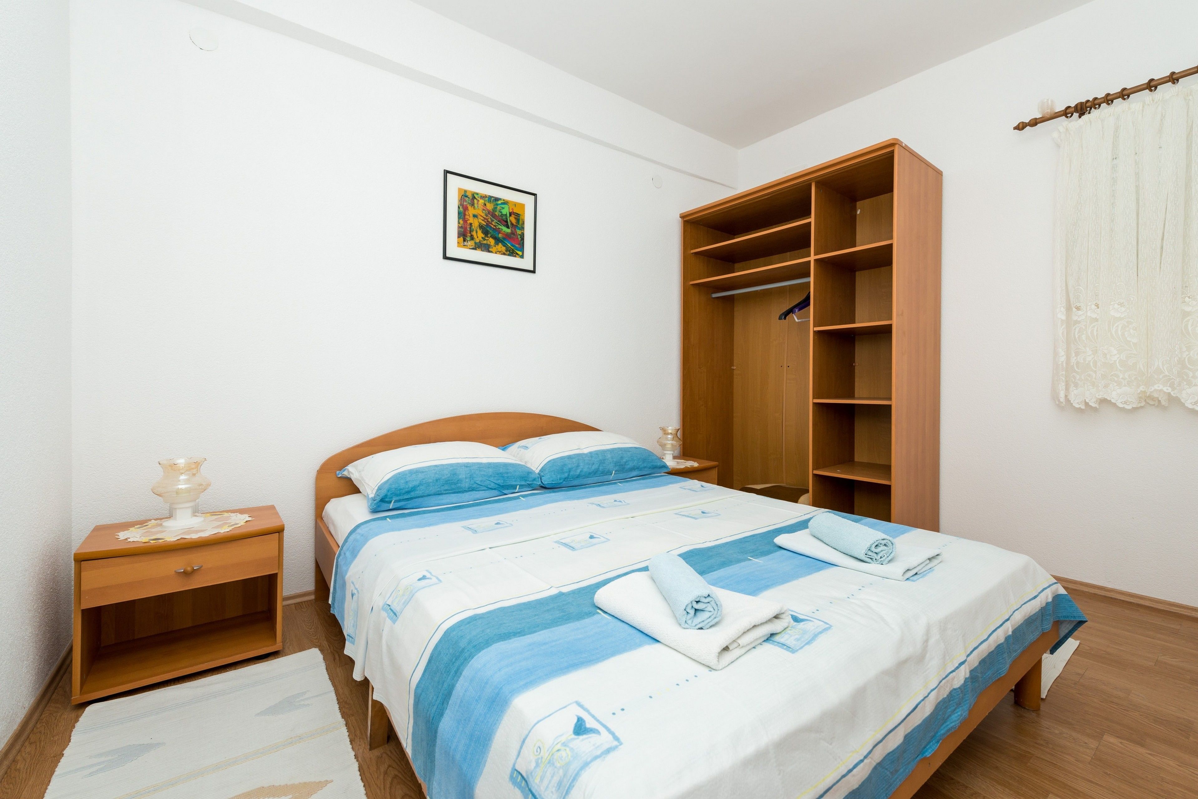 A bedroom with a bed, wooden nightstand, and built-in wardrobe.
